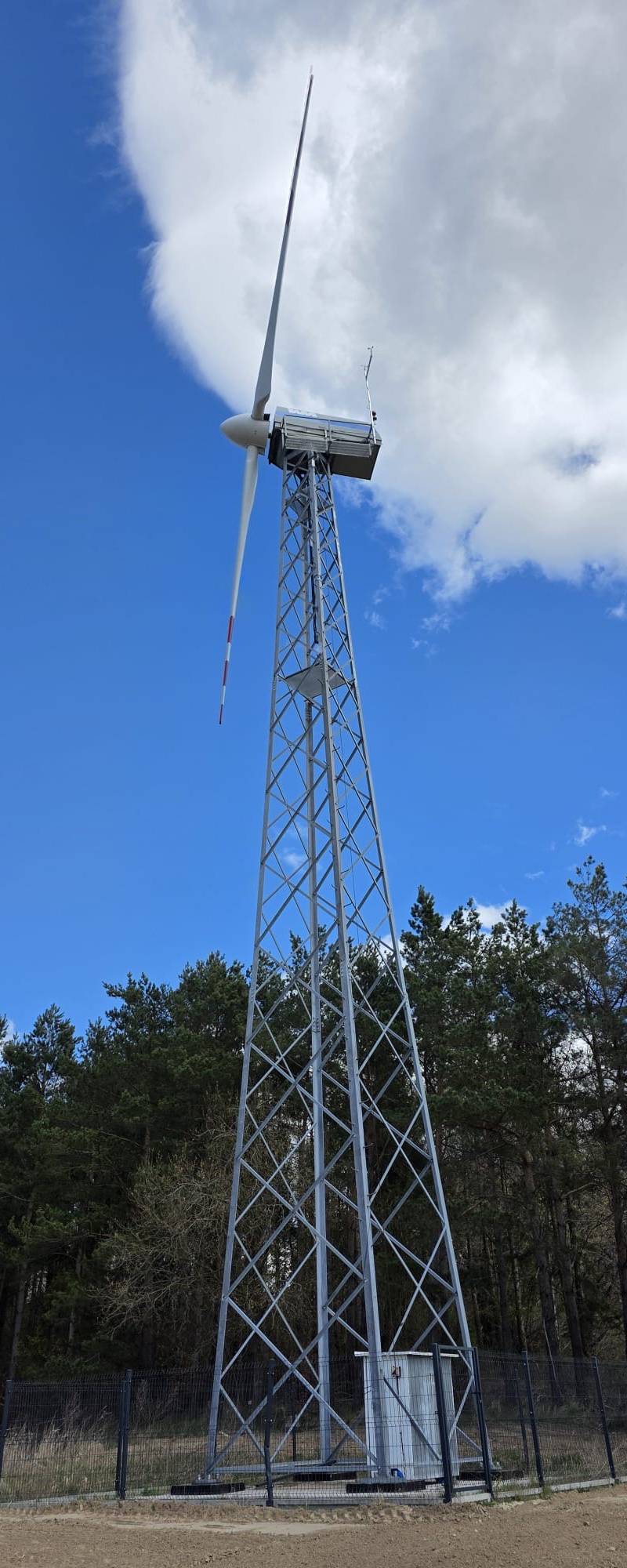 Realizacja FNC Poland - turbina wiatrowa na wysokiej wieży kratowej obok lasu